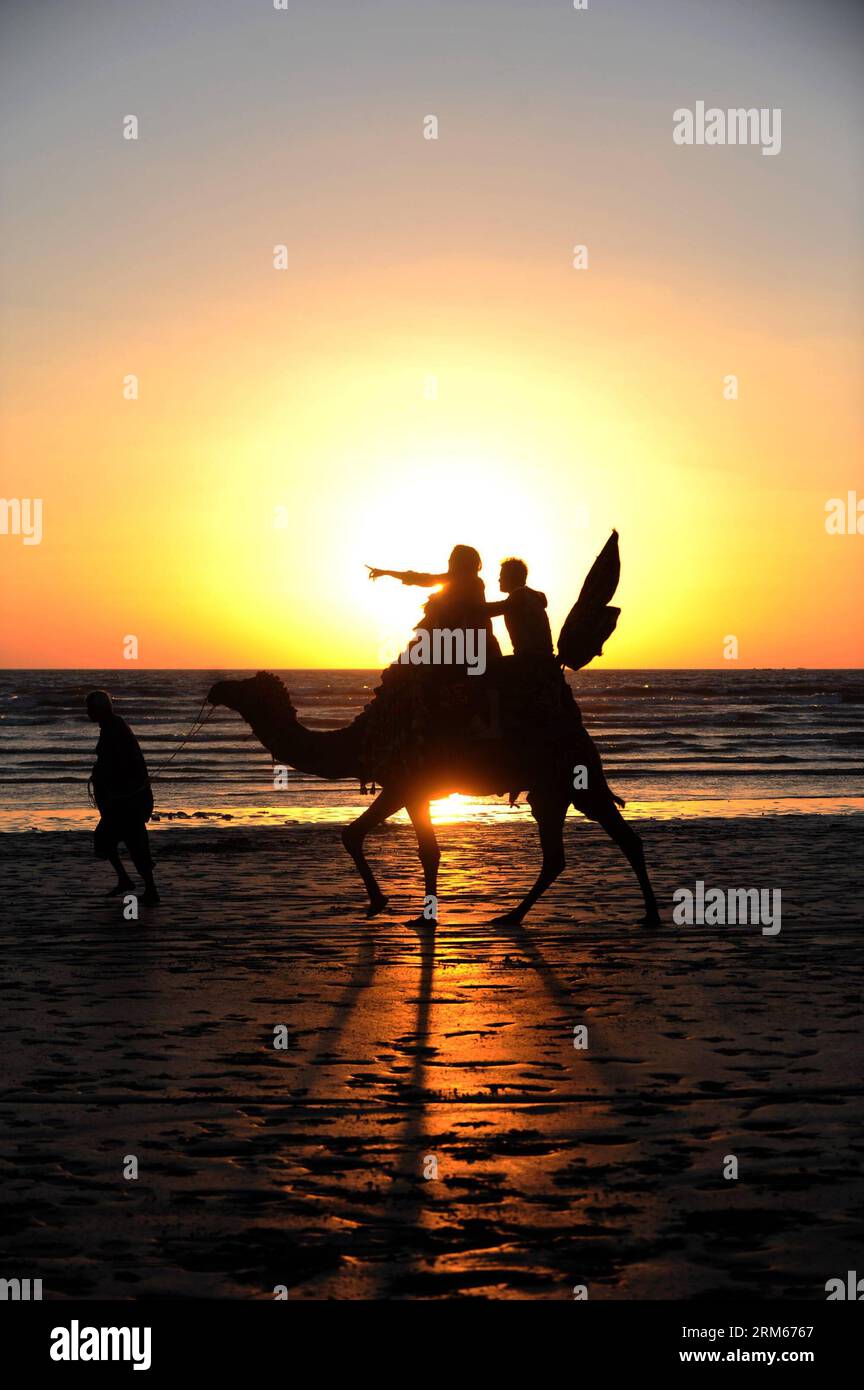 Bildnummer: 60831513  Datum: 14.12.2013  Copyright: imago/Xinhua     Tourists ride on a camel on a beach during sunset in Karachi, Pakistan, on Dec. 14, 2013. (Xinhua/Huang Zongzhi) PAKISTAN-KARACHI-SUNSET PUBLICATIONxNOTxINxCHN xcb x0x 2013 hoch Stock Photo