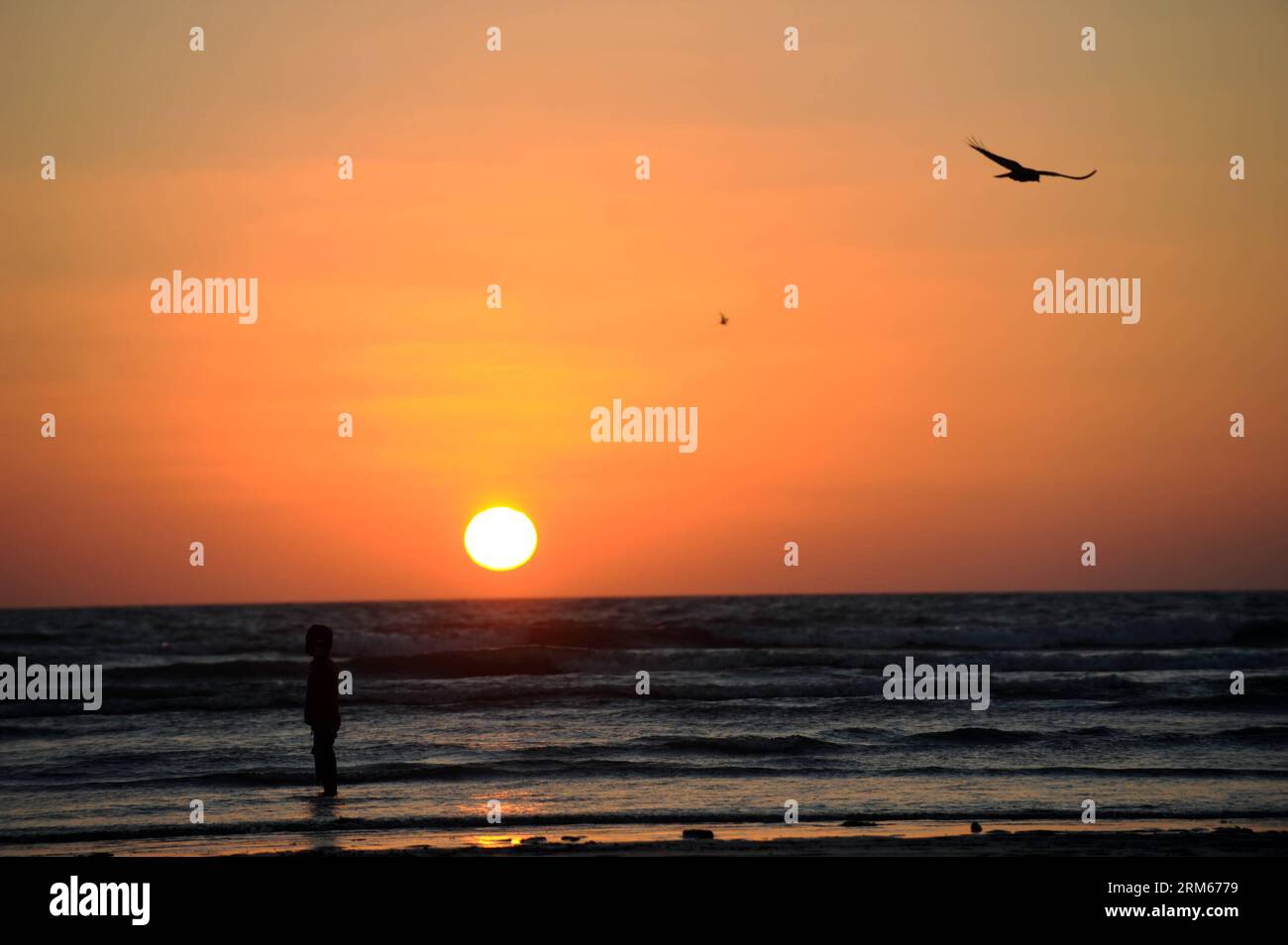Bildnummer: 60831511  Datum: 14.12.2013  Copyright: imago/Xinhua     A boy stands on a beach during sunset in Karachi, Pakistan, on Dec. 14, 2013. (Xinhua/Huang Zongzhi) PAKISTAN-KARACHI-SUNSET PUBLICATIONxNOTxINxCHN xcb x0x 2013 quer Stock Photo