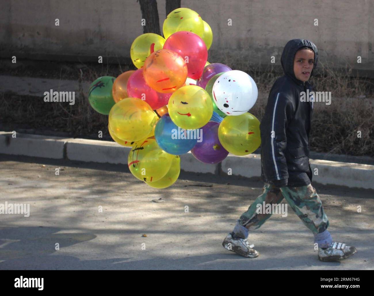 Bildnummer: 60834283  Datum: 16.12.2013  Copyright: imago/Xinhua     (131216) -- KABUL, Dec. 16, 2013 (Xinhua) -- An Afghan child carries ballone for sells in Kabul, Afghanistan, on Dec 16, 2013. (Xinhua/Ahmad Massoud) AFGHANISTAN-KABUL-DAILY LIFE PUBLICATIONxNOTxINxCHN xcb x0x 2013 quer Stock Photo