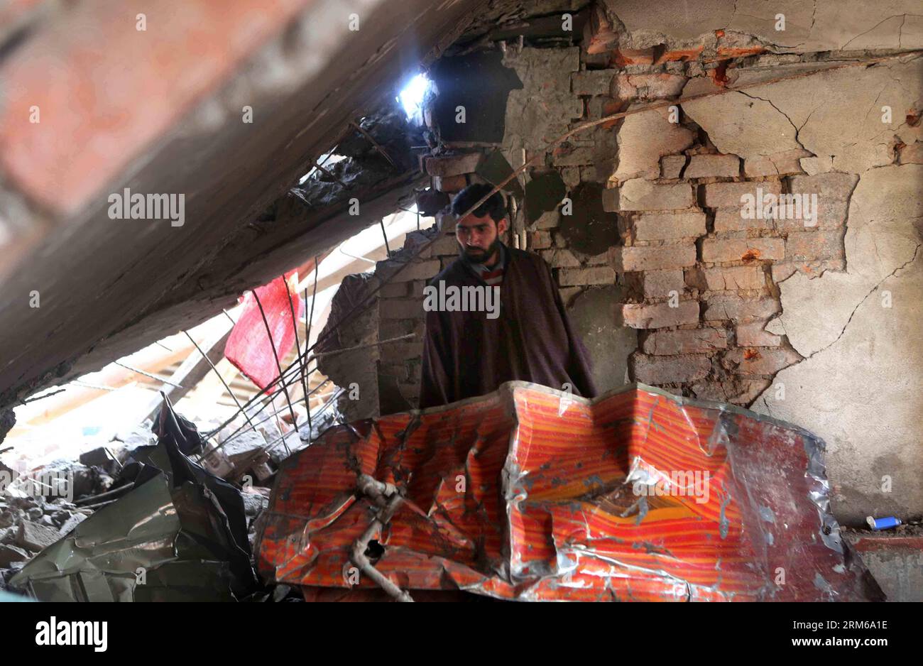 (131226) -- SRINAGAR, Dec. 26, 2013 (Xinhua) -- A Kashmiri villager searches for valuables in the rubbles of a destroyed house after gunfight in village Hushroo, some 30 km south of Srinagar, the summer capital of Indian-controlled Kashmir, Dec. 26, 2013. A militant commander of Lashkar-e-Toiba (LeT) was killed Thursday in a fierce overnight gunfight with Indian troops in Indian- controlled Kashmir, police said. (Xinhua/Javed Dar) KASHMIR-SRINAGAR-GUNFIGHT PUBLICATIONxNOTxINxCHN   Srinagar DEC 26 2013 XINHUA a Kashmiri village searches for valuables in The Rubble of a destroyed House After Gun Stock Photo