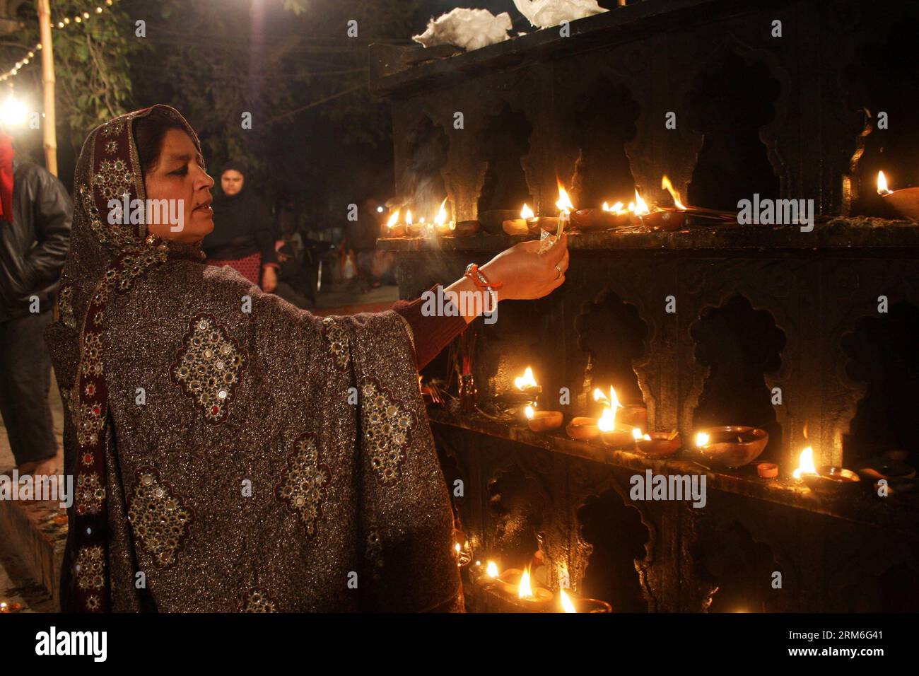(140111) -- LAHORE, Jan. 11, 2014 (Xinhua) -- A Pakistani Muslim devotee lights oil lamps at the shrine of the Sufi saint Mian Mir Sahib during the last day of a three-day festival marking his 369th death anniversary in eastern Pakistan s Lahore on Jan. 11, 2014. (Xinhua/Jamil Ahmed) (djj) PAKISTAN-LAHORE-RELIGION-SHRINE PUBLICATIONxNOTxINxCHN   Lahore Jan 11 2014 XINHUA a Pakistani Muslim devotee Lights Oil lamps AT The Shrine of The Sufi Saint Mian me Sahib during The Load Day of a Three Day Festival marking His  Death Anniversary in Eastern Pakistan S Lahore ON Jan 11 2014 XINHUA Jamil Ahme Stock Photo