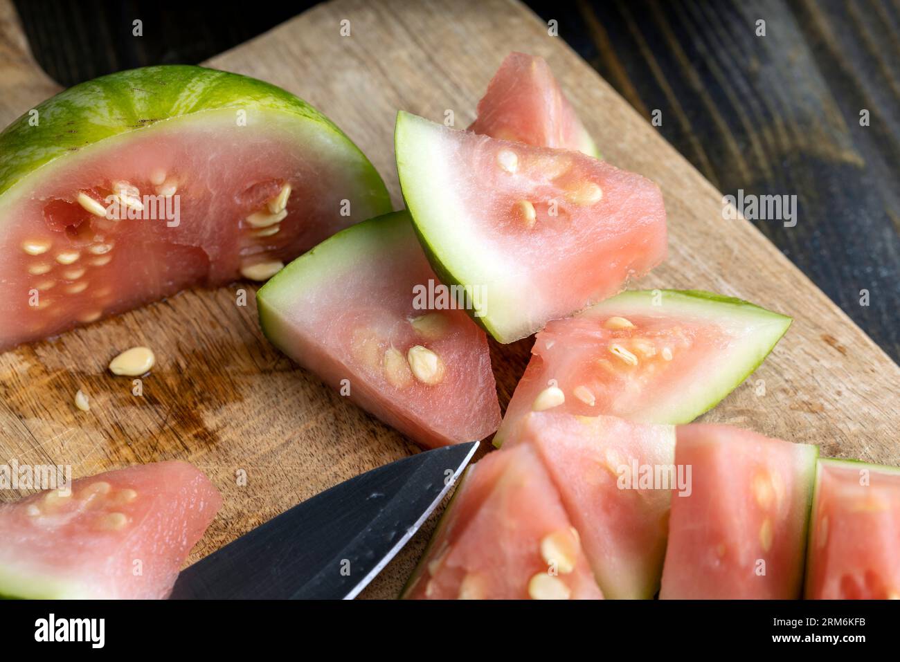 not sweet not ripe cut watermelon, Unripe watermelon of small size with large white seeds and light pink flesh Stock Photo