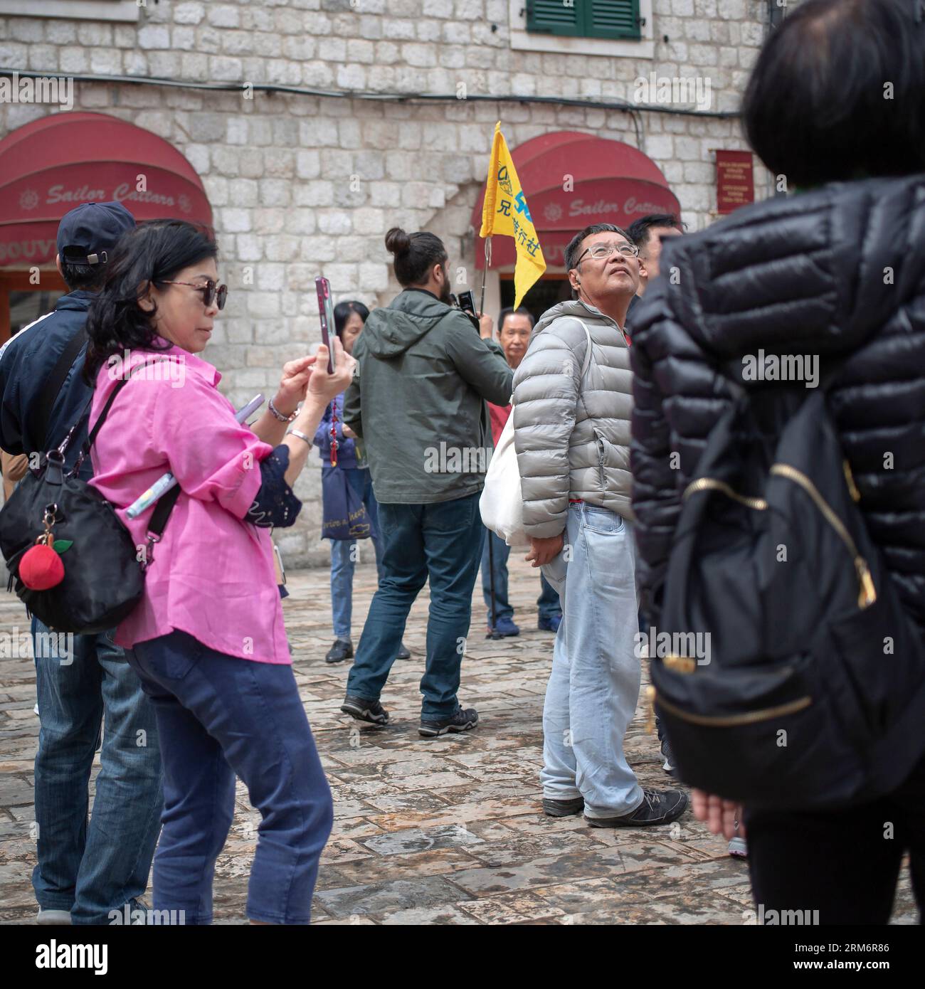 Montenegro, Apr 17, 2023: A group of Chinese tourists sightseeing at the Square of the Arms in Kotor Old Town Stock Photo