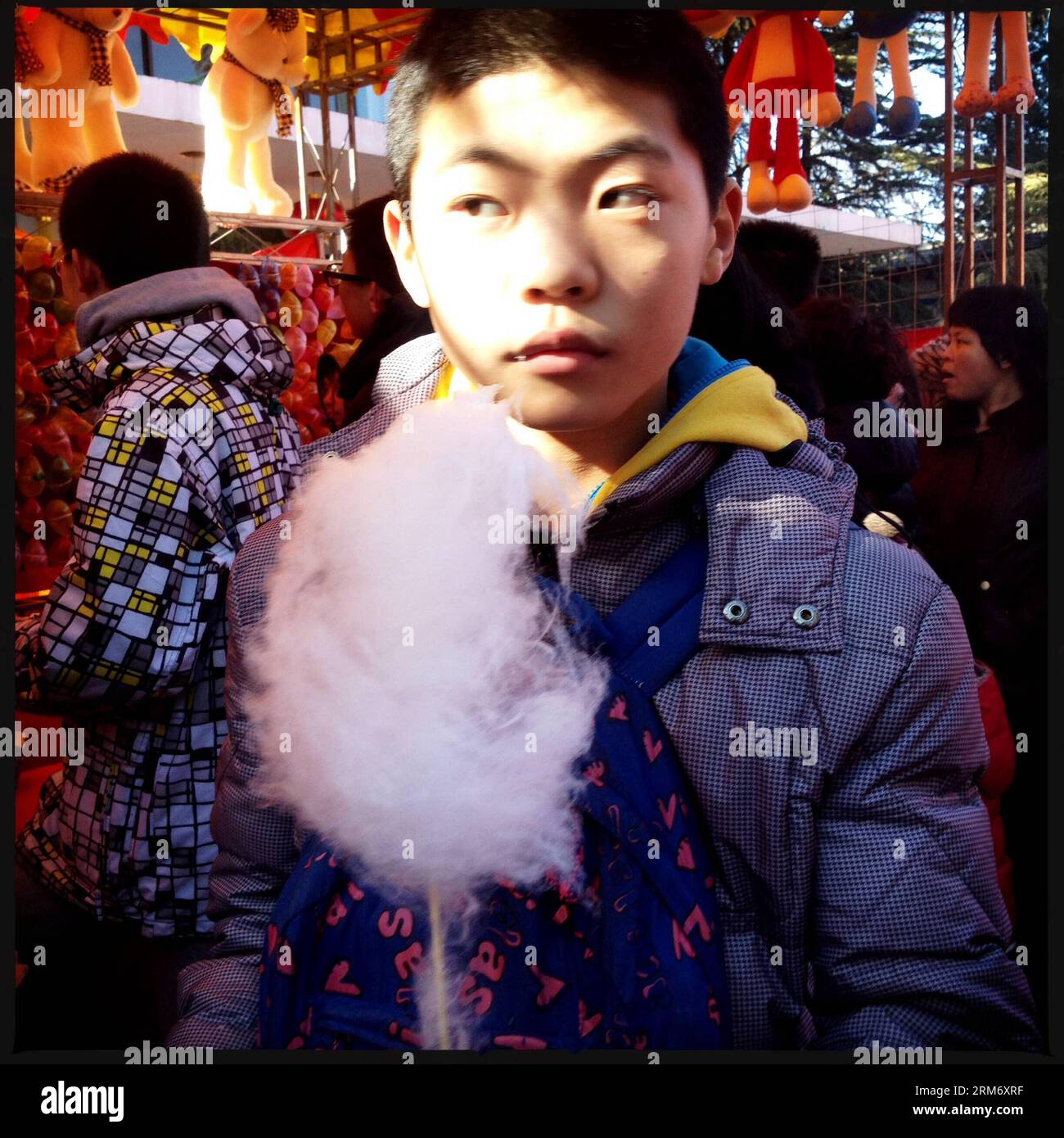 (140203) -- BEIJING, Feb. 3, 2014 (Xinhua) -- In this photo taken with a smartphone on Feb. 3, 2014, a young boy holding a cotton candy is attracted by a game tournament at the Changdian Temple Fair in Beijing, capital of China. In Beijing, temple fairs have been a typical repertoire during the Spring Festival, which fell on Jan. 31 this year. People entertain themselves at temple fairs with various food and snacks as well as folk activities. (Xinhua/Shen Bohan) (lmm) CHINA-BEIJING-SPRING FESTIVAL-TEMPLE FAIR-SMARTPHONE (CN) PUBLICATIONxNOTxINxCHN   Beijing Feb 3 2014 XINHUA in This Photo Take Stock Photo