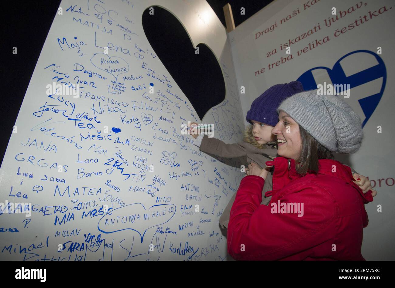A kid signs her name on a huge card during the Lampionovo Lantern Festival in Zapresic, Croatia, Feb. 14, 2014. People released lanterns carrying their hopes and best wishes during the festival on Friday, and signed a huge Valentine s Day card to their twin town of Kastela. (Xinhua/Miso Lisanin) (zhf) CROATIA-ZAPRESIC-LANTERN FESTIVAL PUBLICATIONxNOTxINxCHN   a Kid Signs her Name ON a Huge Card during The  Lantern Festival in  Croatia Feb 14 2014 Celebrities released Lanterns carrying their Hopes and Best wishes during The Festival ON Friday and signed a Huge Valentine S Day Card to their Twin Stock Photo