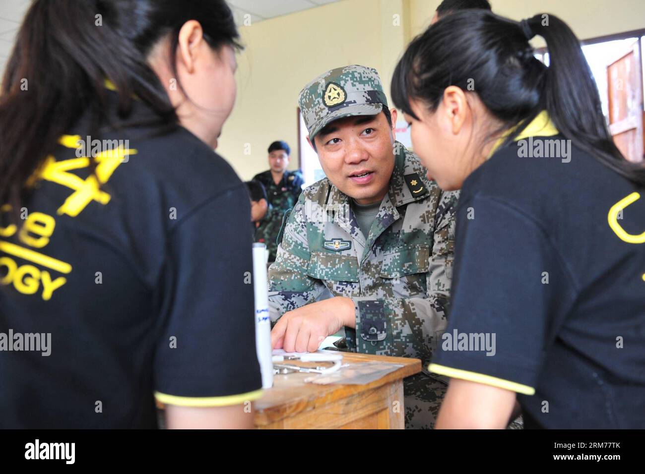 (140218) -- PITSANULOKE, Feb. 18, 2014 (Xinhua) -- A staff member of medical team from the Chinese military gives medical advice to locals at a school in Pitsanuloke Province, Thailand, Feb. 18, 2014. China has sent troops to attend the multilateral military exercise Cobra Gold, led by the United States and Thailand, for the first time. The seventeen-strong Chinese squad will take part in operations at the command and coordination center, engineering assistance, medical aid as well as discussions and exchanges of military medical sciences, according to officers with the foreign affairs office Stock Photo