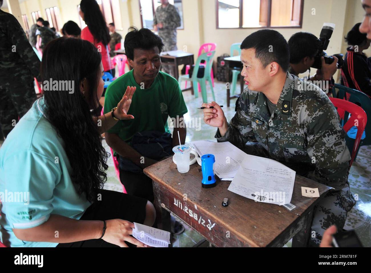 (140218) -- PITSANULOKE, Feb. 18, 2014 (Xinhua) -- A staff member of medical team from the Chinese military gives medical advice to locals at a school in Pitsanuloke Province, Thailand, Feb. 18, 2014. China has sent troops to attend the multilateral military exercise Cobra Gold, led by the United States and Thailand, for the first time. The seventeen-strong Chinese squad will take part in operations at the command and coordination center, engineering assistance, medical aid as well as discussions and exchanges of military medical sciences, according to officers with the foreign affairs office Stock Photo