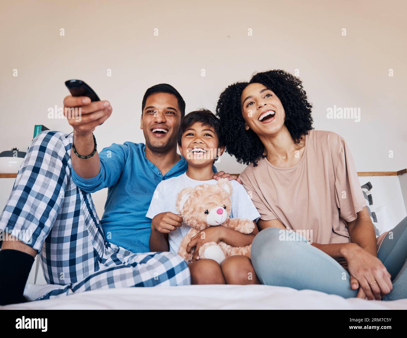 Smile, morning and family watching tv in a bedroom of their home together for streaming or entertainment. Parents, children or a boy laughing on the Stock Photo