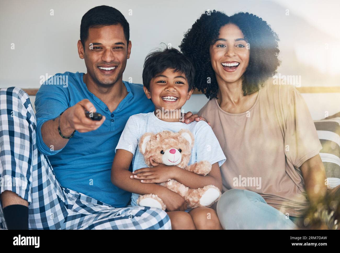 Happy, morning and a family watching tv on bed in their home together for streaming or entertainment. Parents, children or funny boy in the bedroom Stock Photo