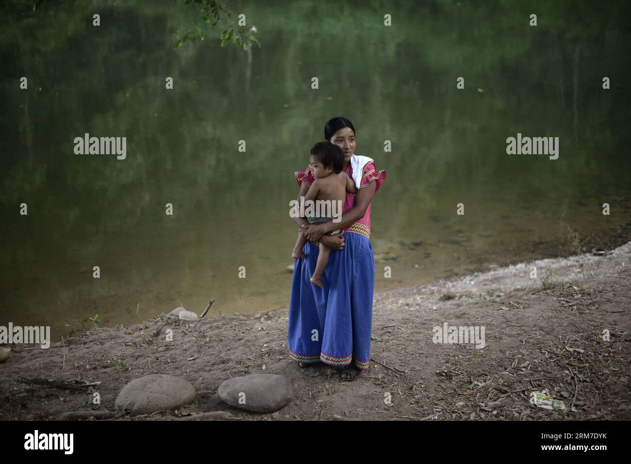 A woman of the Ngabe Bugle ethnic group carries her baby in a camp near the Tabasara river bank in the Ngabe Bugle indigenous region, 450 km west of Panama City, capital of Panama, on Feb. 24, 2014. The Ngabe Bugle indigenous region is located in the western region of Panama, and covers an area of 6,968 square km, with 91 per cent of its population living in extreme poverty. Native leaders of the Ngabe Bugle region declared a national alert , because of the eviction notice issued by a company which is developing the hydro-electric project Barro Blanco . The project will use the water from Taba Stock Photo