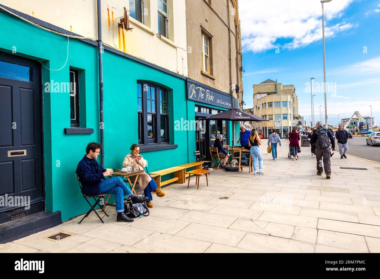 People sitting at On the Rocks cafe at Hastings seafront, East Sussex, England Stock Photo