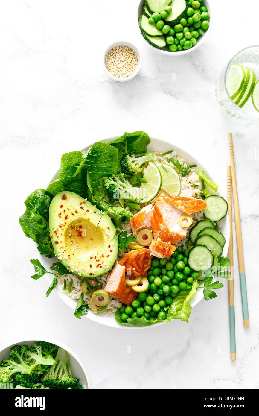 Salmon avocado bowl with broccoli, green peas, rice and fresh salad. Healthy food, top view Stock Photo