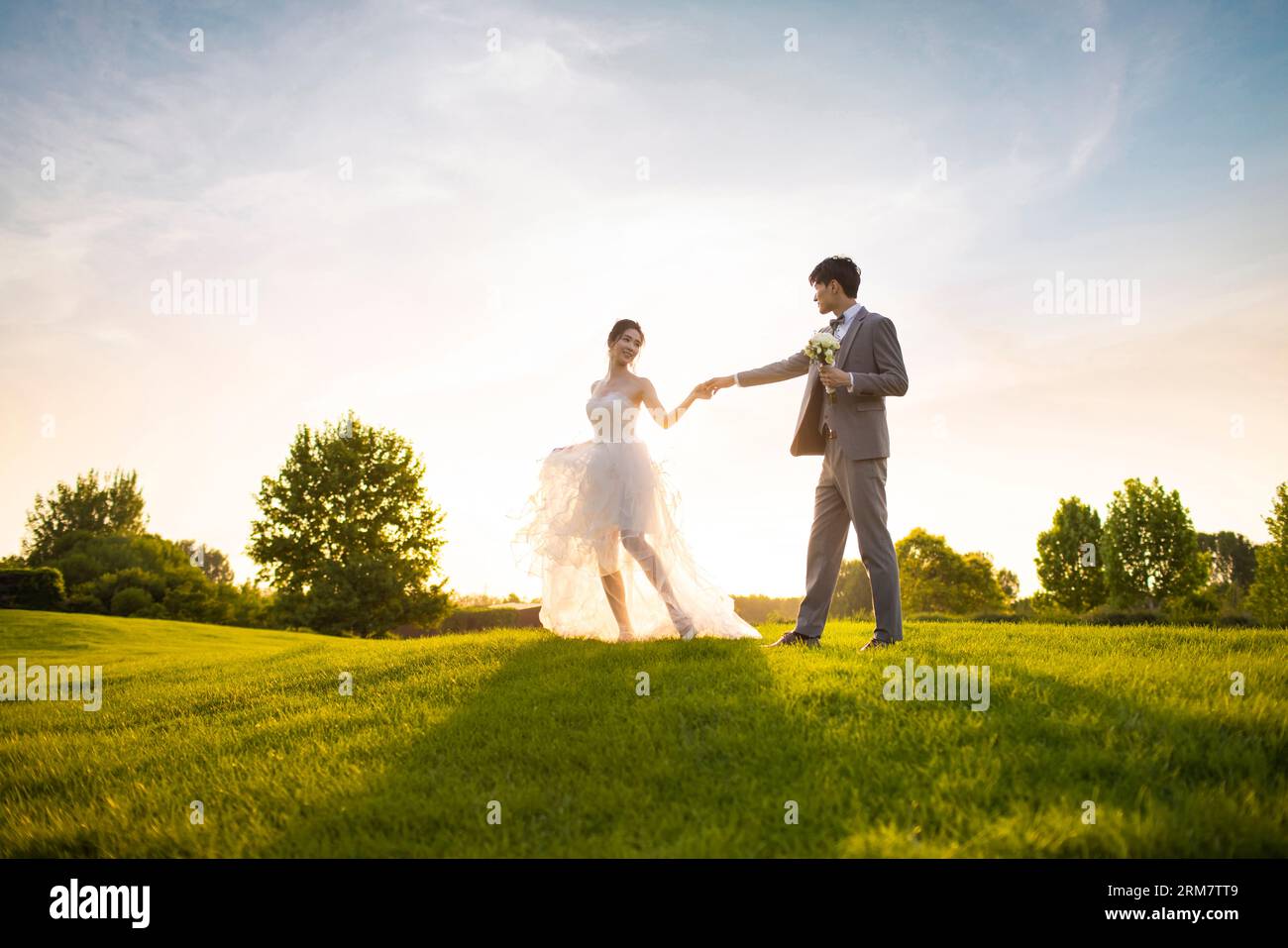 Happy bride and groom dancing on the grass Stock Photo