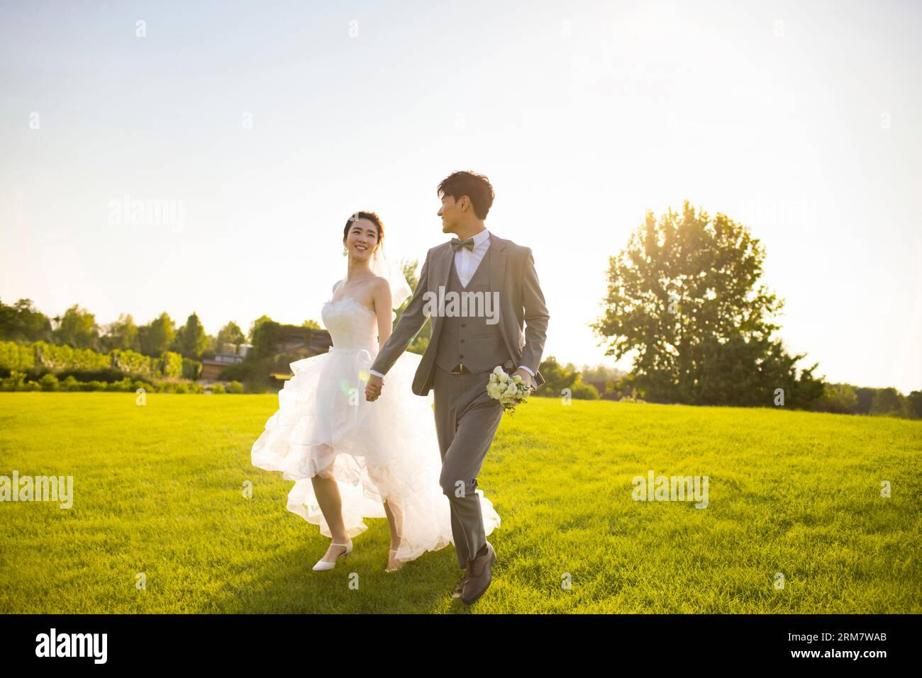 Happy bride and groom running on the grass Stock Photo