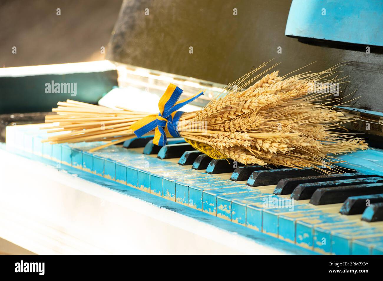 A piano, and next to the keys lies a bunch of wheat with the flag of Ukraine on the street of the city of Dnipro in Ukraine, plays the piano Stock Photo