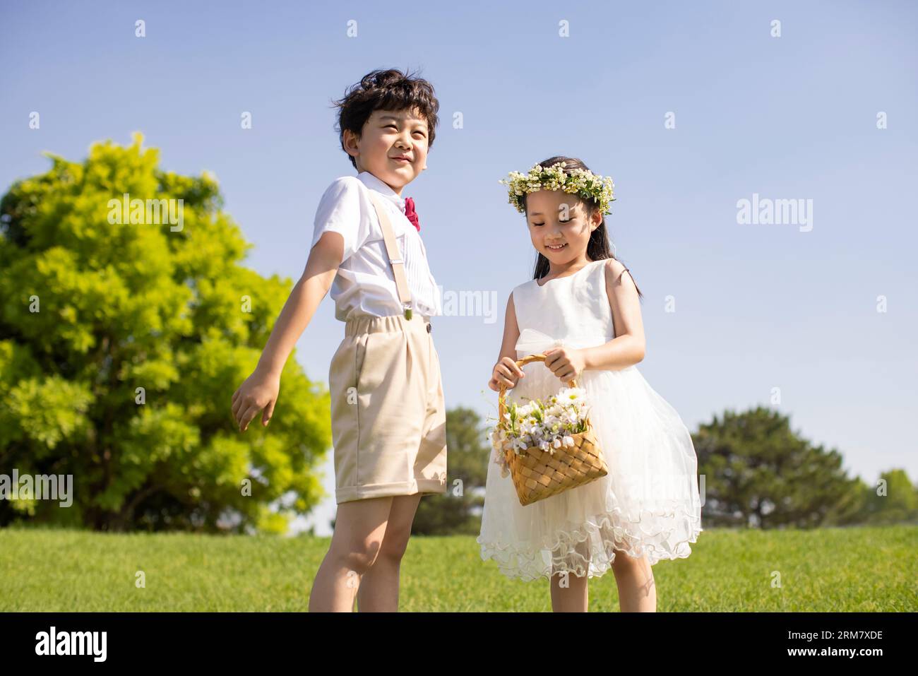 Cute flower girl and ring bearer playing on the grass Stock Photo