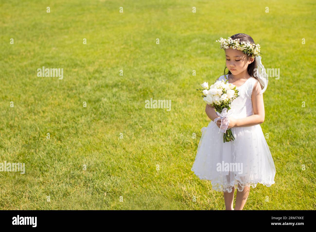 Cute flower girl holding a bunch of flowers Stock Photo