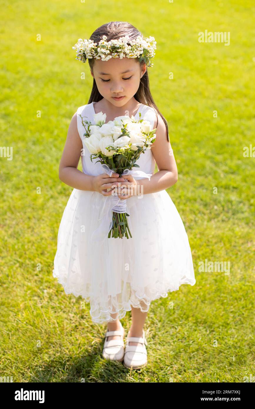 Cute flower girl holding a bunch of flowers Stock Photo - Alamy