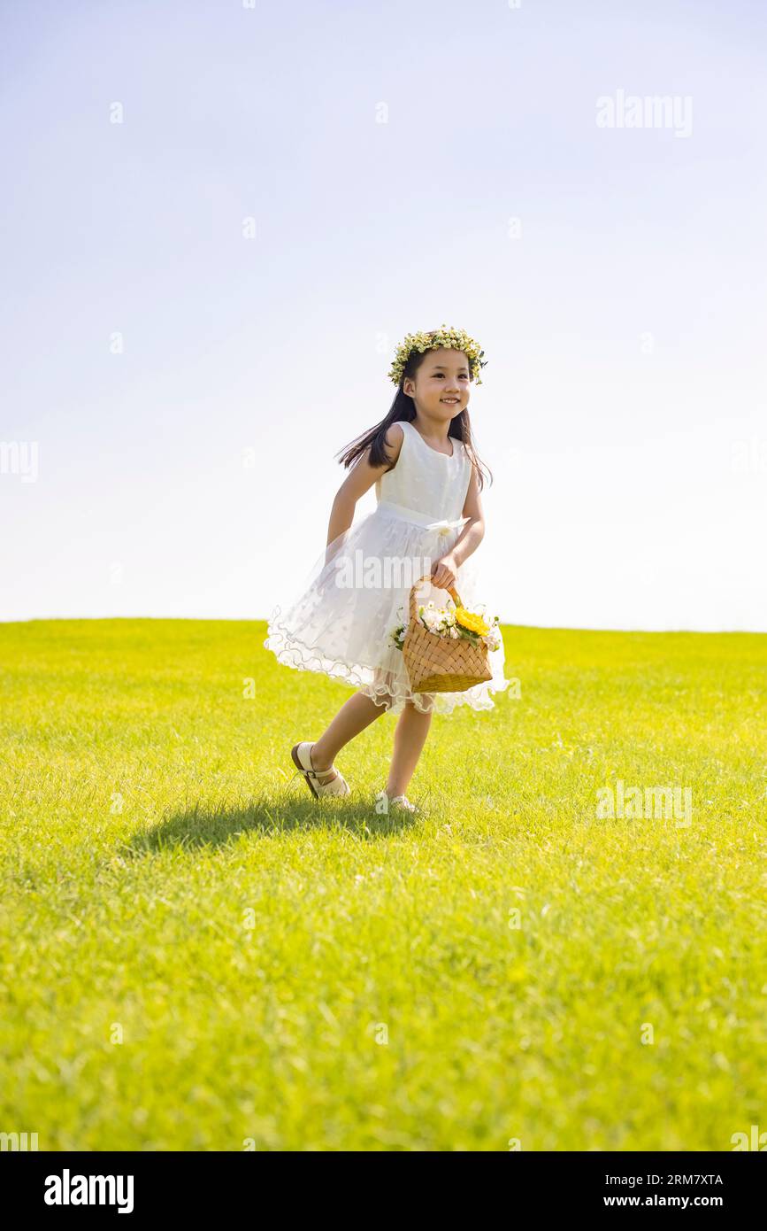 Cute flower girl playing on the grass Stock Photo