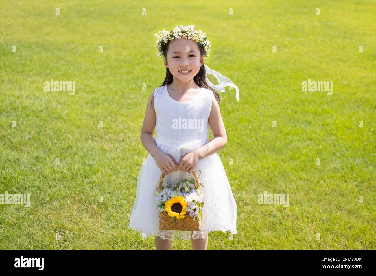 Cute flower girl standing on the grass Stock Photo