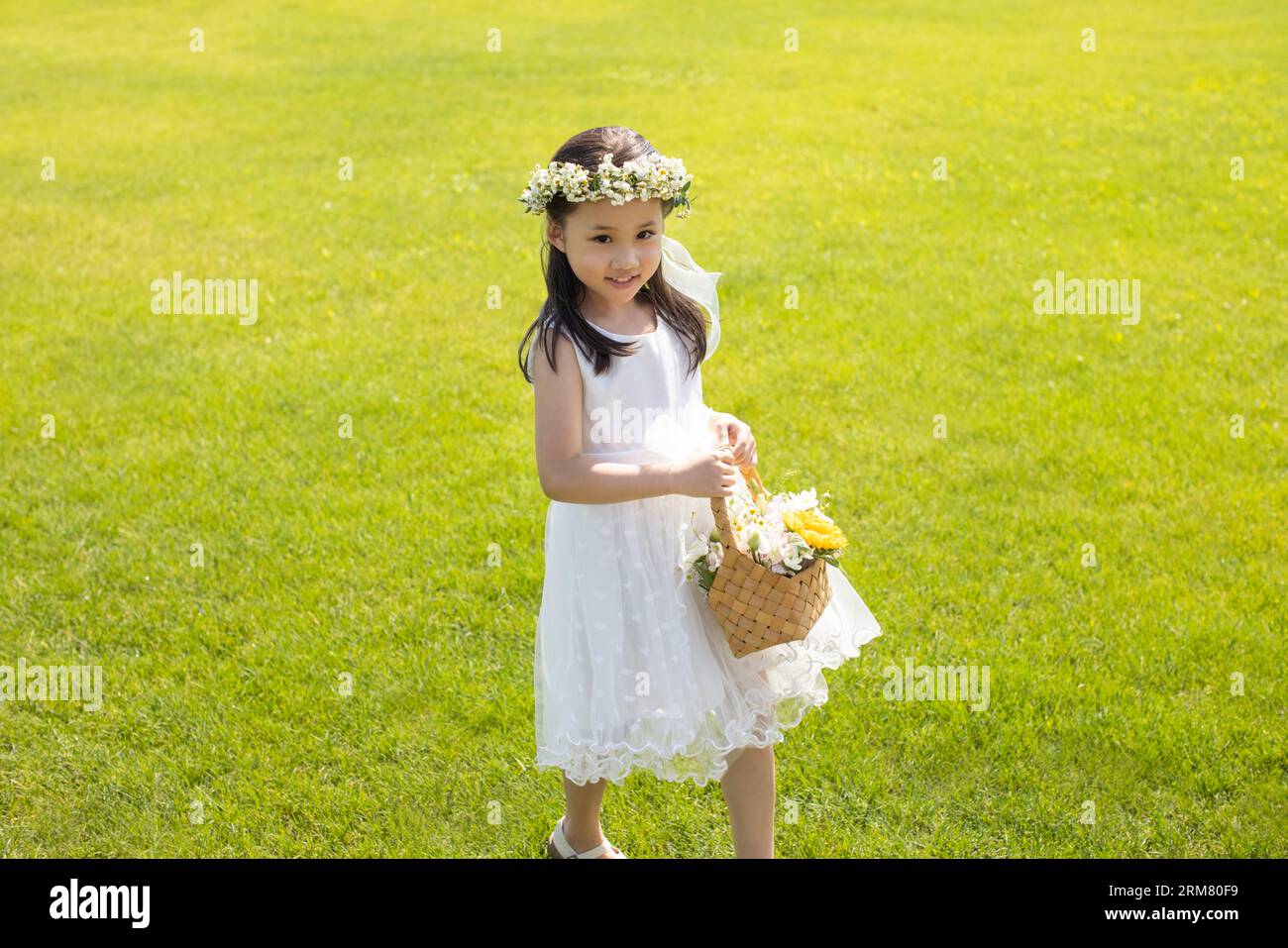 Cute flower girl playing on the grass Stock Photo