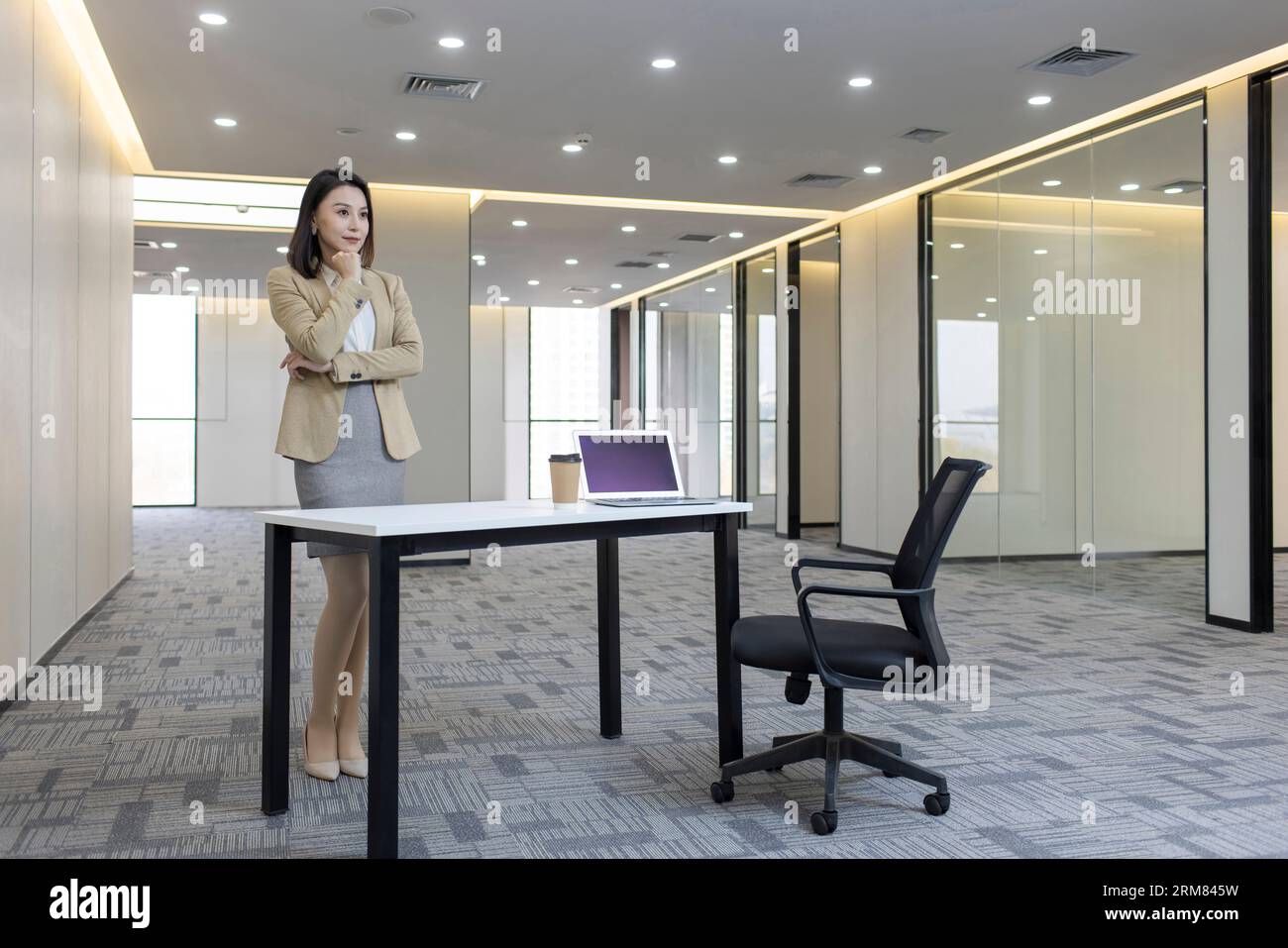 Confident businesswoman thinking in empty office Stock Photo