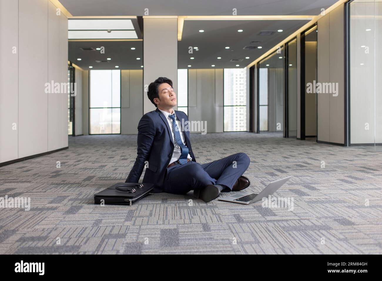 Businessman sitting on floor in empty office Stock Photo