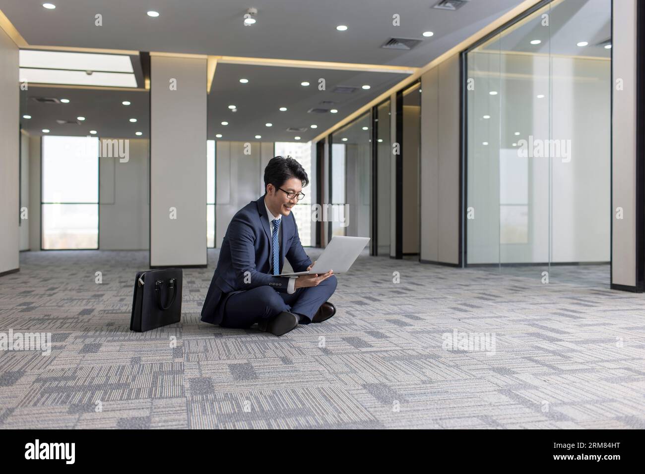Businessman using laptop on floor in empty office Stock Photo