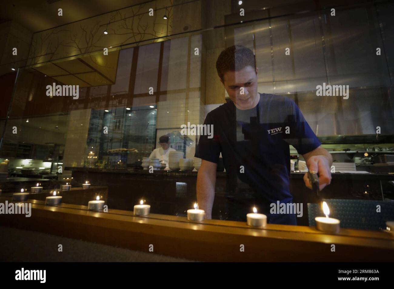 VANCOUVER, March 29, 2014 (Xinhua) -- A waiter lights up candles on tables as the restaurant turned out the lights for Earth Hour at a restaurant in downtown Vancouver, Canada, March 29, 2014. The Earth Hour is held worldwide annually to encourage people to turn off the lights for one hour to promote an idea of environmental awareness. (Xinhua/Liang Sen) CANADA-VANCOUVER-EARTH HOUR PUBLICATIONxNOTxINxCHN   Vancouver March 29 2014 XINHUA a Waiter Lights up Candles ON Tables As The Restaurant turned out The Lights for Earth hour AT a Restaurant in Downtown Vancouver Canada March 29 2014 The Eart Stock Photo