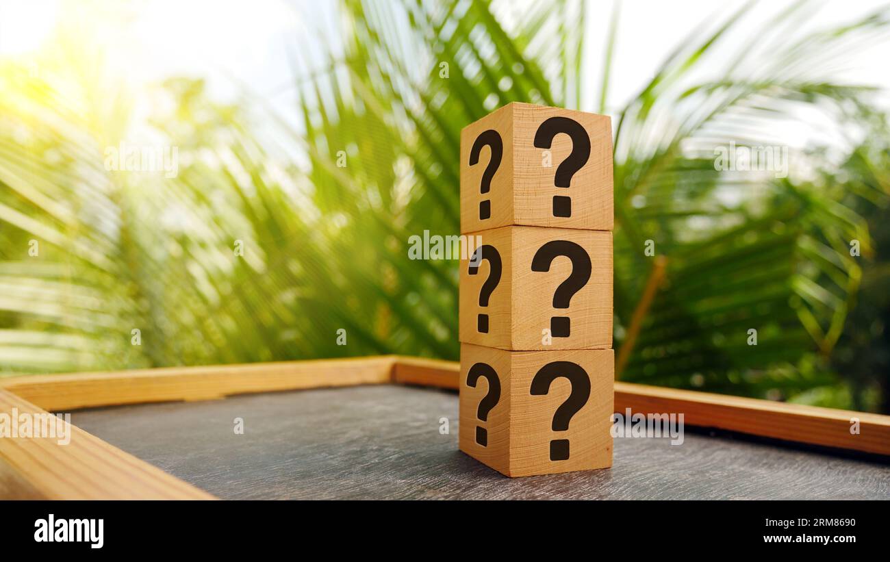 Stack of three wooden cubes with question mark over nature background with sunlight with copy space Stock Photo