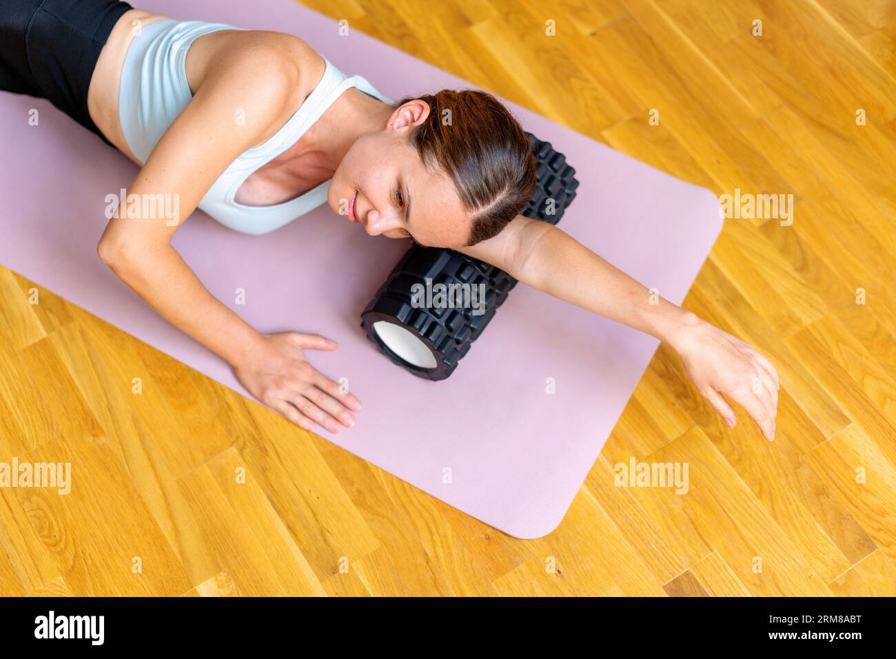 Roman using foam roller for reducing soreness and increasing flexibility of muscles of arms. Stock Photo