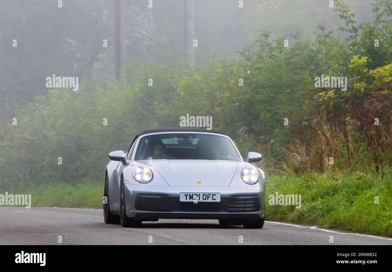 Whittlebury,Northants,UK -Aug 26th 2023: 2021 silver Porsche 911 Carrera S car travelling on an English country road on a damp and misty morning. Stock Photo