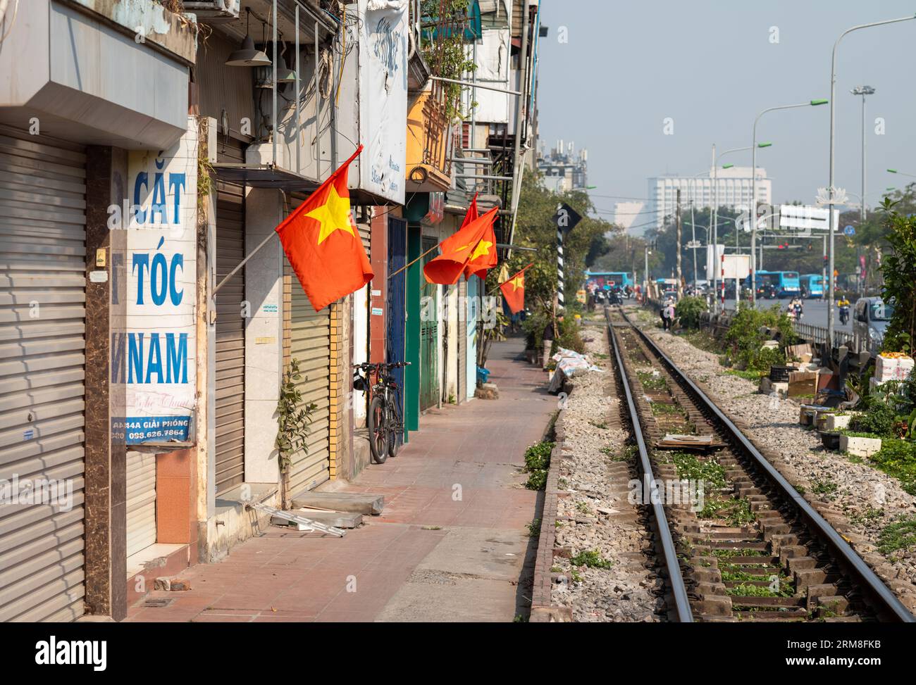 Vietnamese goldstarred red flags fly on poles outside shuttered shops alongside the main north