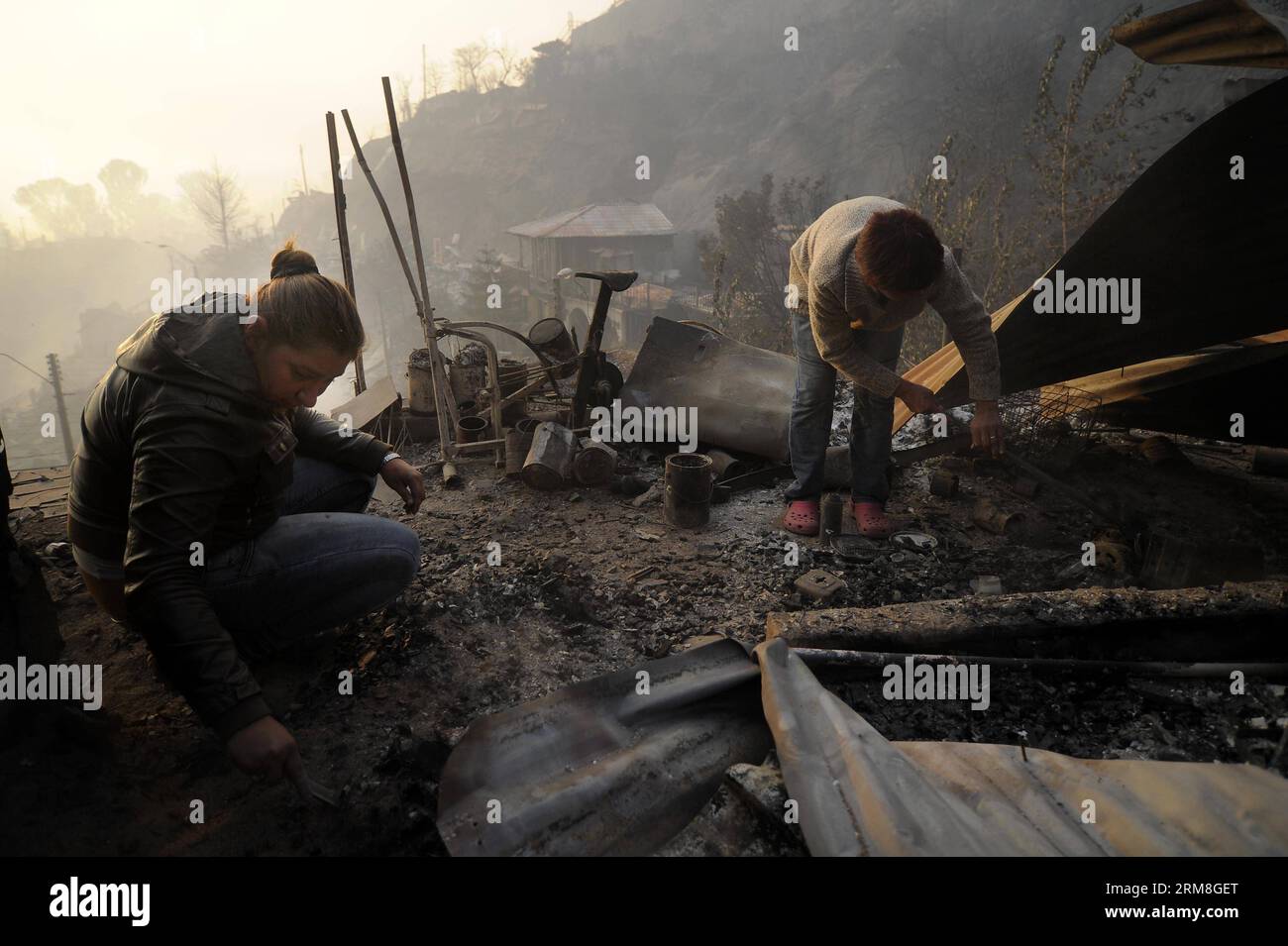 Residents search for their belongings in a house destroyed by a fire in Valparaiso, Chile on April 13, 2014. At least 11 people were killed over the weekend in a massive forest fire that broke out in Chile s port city of Valparaiso, authorities said Sunday. President Michelle Bachelet declared state of emergency in the city and sent the army in to maintain order as thousands of residents were evacuated. (Xinhua/Pablo Ovalle/AGENCIA UNO) CHILE-VALPARAISO-FIRE PUBLICATIONxNOTxINxCHN   Residents Search for their belonging in a House destroyed by a Fire in Valparaiso Chile ON April 13 2014 AT leas Stock Photo