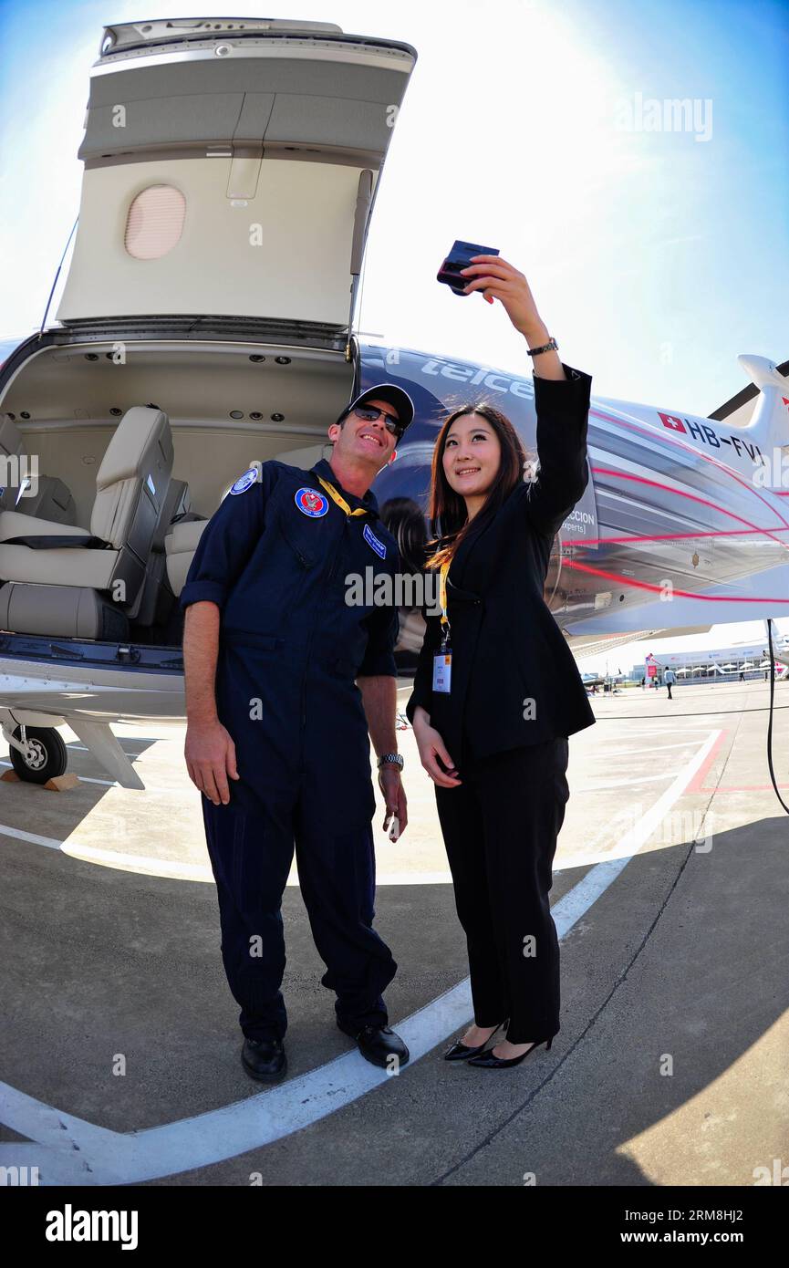 (140415) -- SHANGHAI, April 15, 2014 (Xinhua) -- A visitor poses for photos with a pilot in front of a Pilatus PC-12 business airplane at the 2014 Asian Business Aviation Conference & Exhibition (ABACE2014) in east China s Shanghai, April 15, 2014. ABACE2014, Asia s largest business aviation product and services event, kicked off Tuesday in Shanghai. Thirty-eight business aircrafts made by 20 manufacturers, including Boeing, Airbus and Bombardier, will be displayed during the three-day event. Their prices range from 3 million yuan (482,000 U.S. dollars) to 560 million yuan (89.99 million U.S. Stock Photo