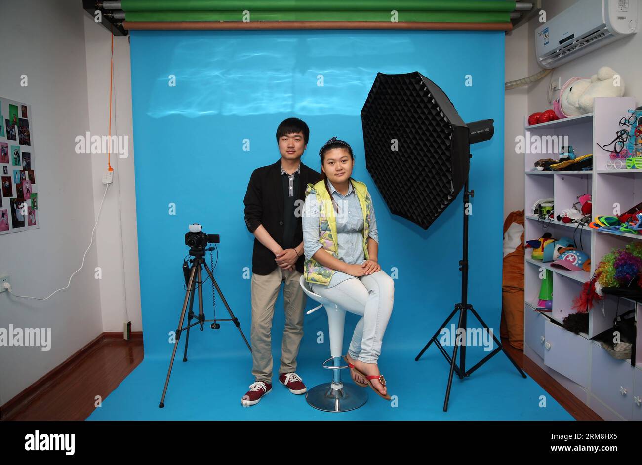 CHANGSHA, April 15, 2014 (Xinhua) -- Zeng Jun (L) and Yuan Chunzi pose for photos at their photo studio Takaphotoo in Changsha, capital of central China s Hunan Province, April 15, 2014. In March, Zeng Jun and his college classmate Yuan Chunzi opened up Takaphotoo, a self-service photo studio in which customers are allowed to shoot pictures for themselves. In a photo booth where the camera and lighting are already set, what customers need to do is to pose in front of the lens and press the remote shutter. The two young entrepreneurs believe this will make their customers feel more relaxed and Stock Photo