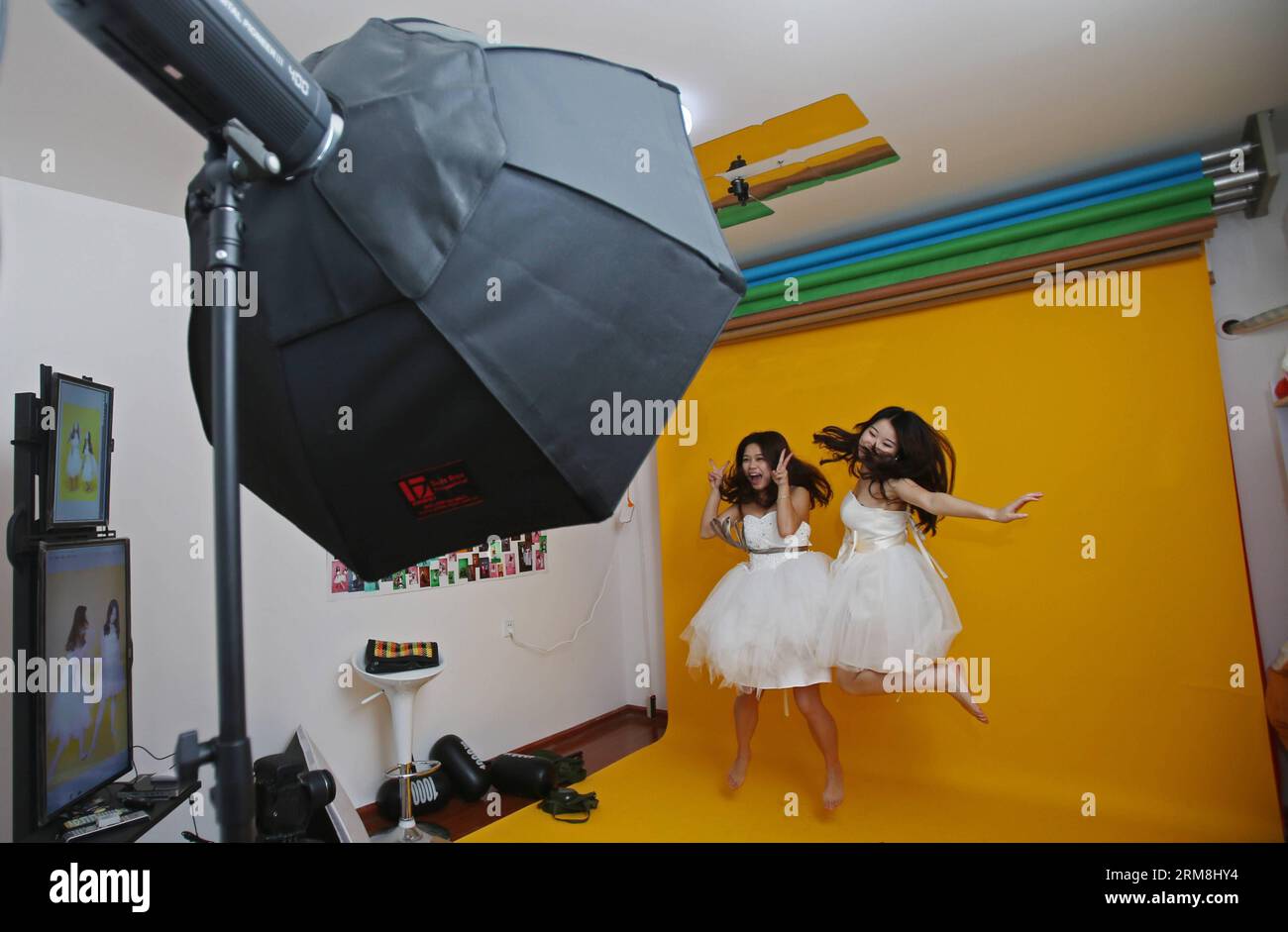 CHANGSHA, April 15, 2014 (Xinhua) -- Two customers take portraits for themselves at Zeng Jun s photo studio Takaphotoo in Changsha, capital of central China s Hunan Province, April 15, 2014. In March, Zeng Jun and his college classmate Yuan Chunzi opened up Takaphotoo, a self-service photo studio in which customers are allowed to shoot pictures for themselves. In a photo booth where the camera and lighting are already set, what customers need to do is to pose in front of the lens and press the remote shutter. The two young entrepreneurs believe this will make their customers feel more relaxed Stock Photo
