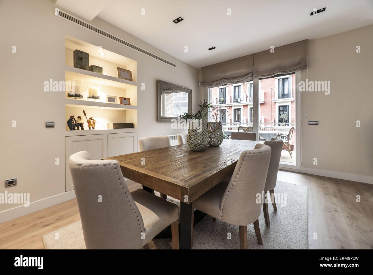 A large wooden dining table flanked by pale fabric upholstered chairs