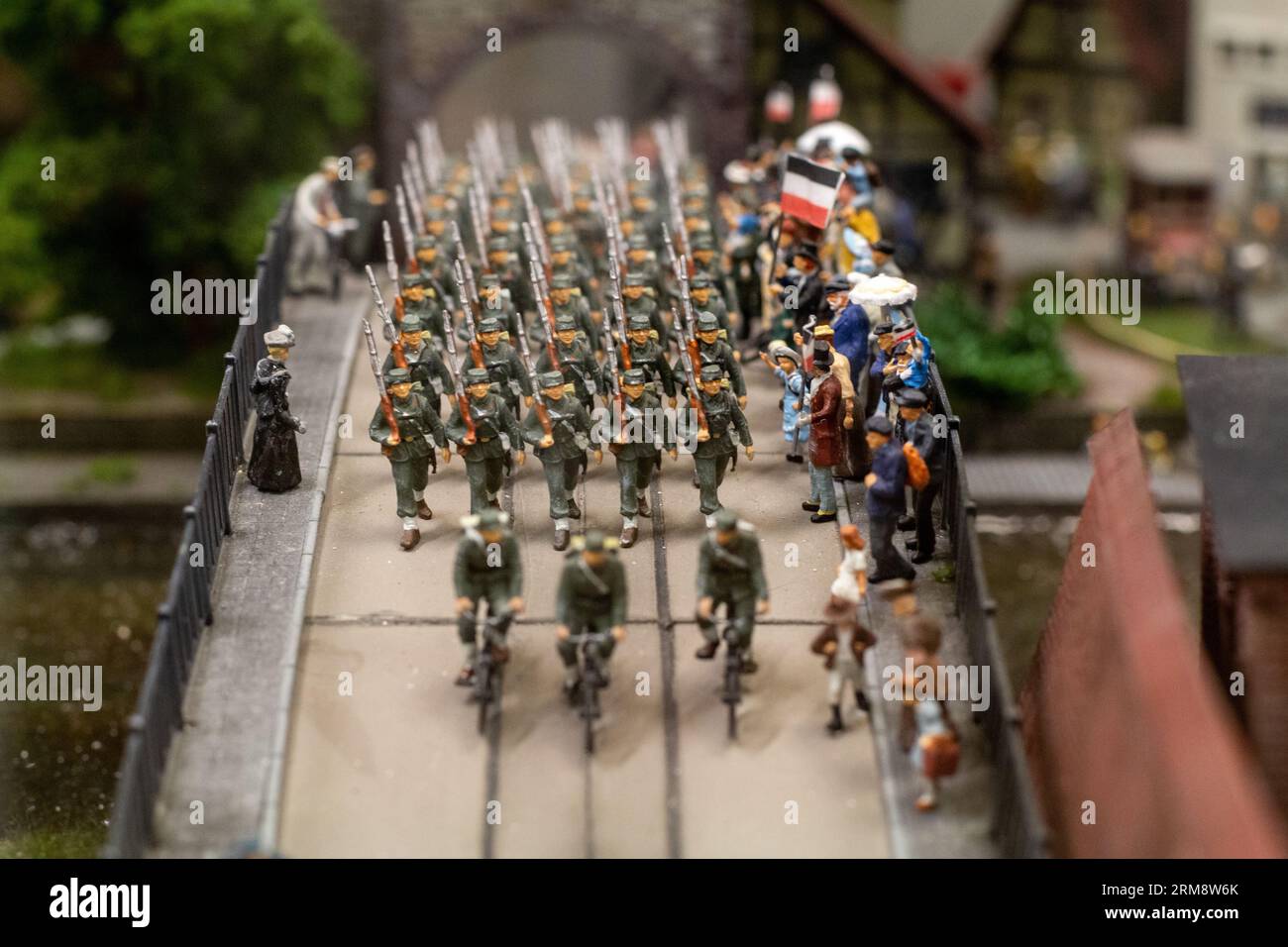 Miniature diorama at Miniatur Wunderland in Hamburg, Germany, depicting soldiers parading across a bridge through a group of civilians Stock Photo