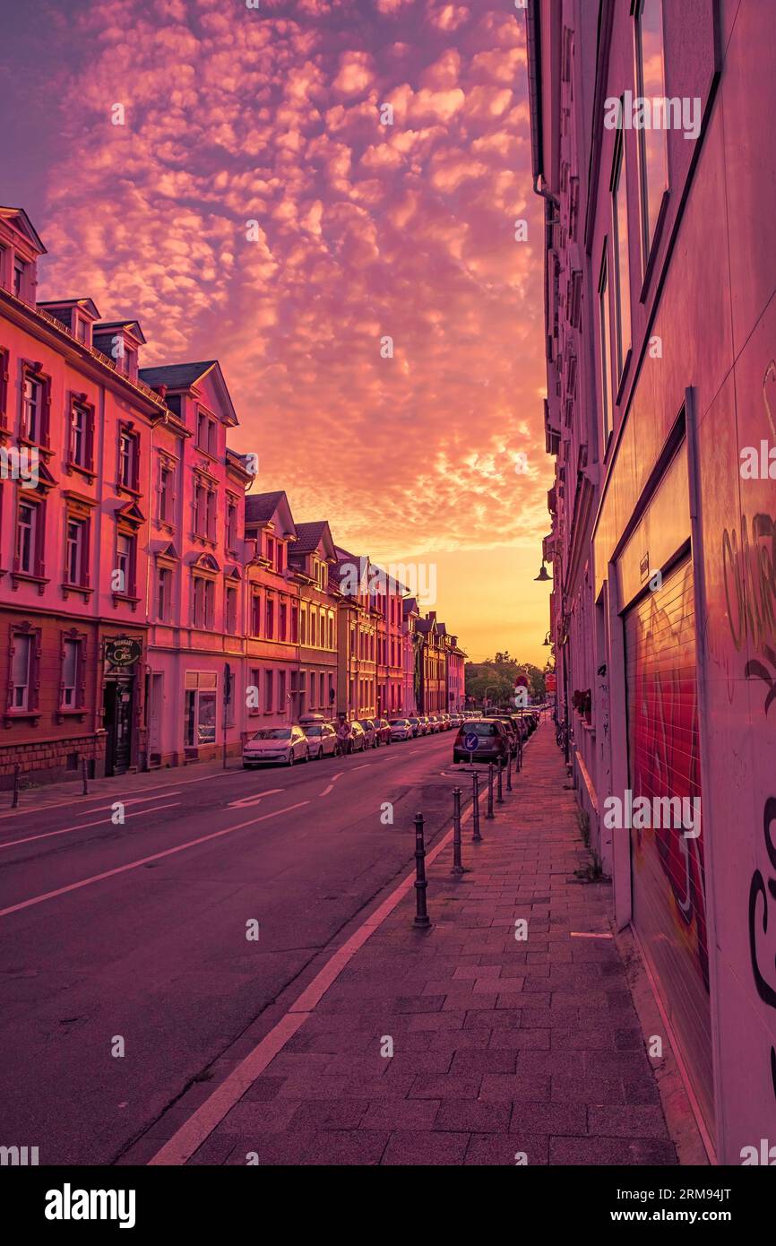sunset on the street in Germany with warm color clouds and nearly empty street Stock Photo