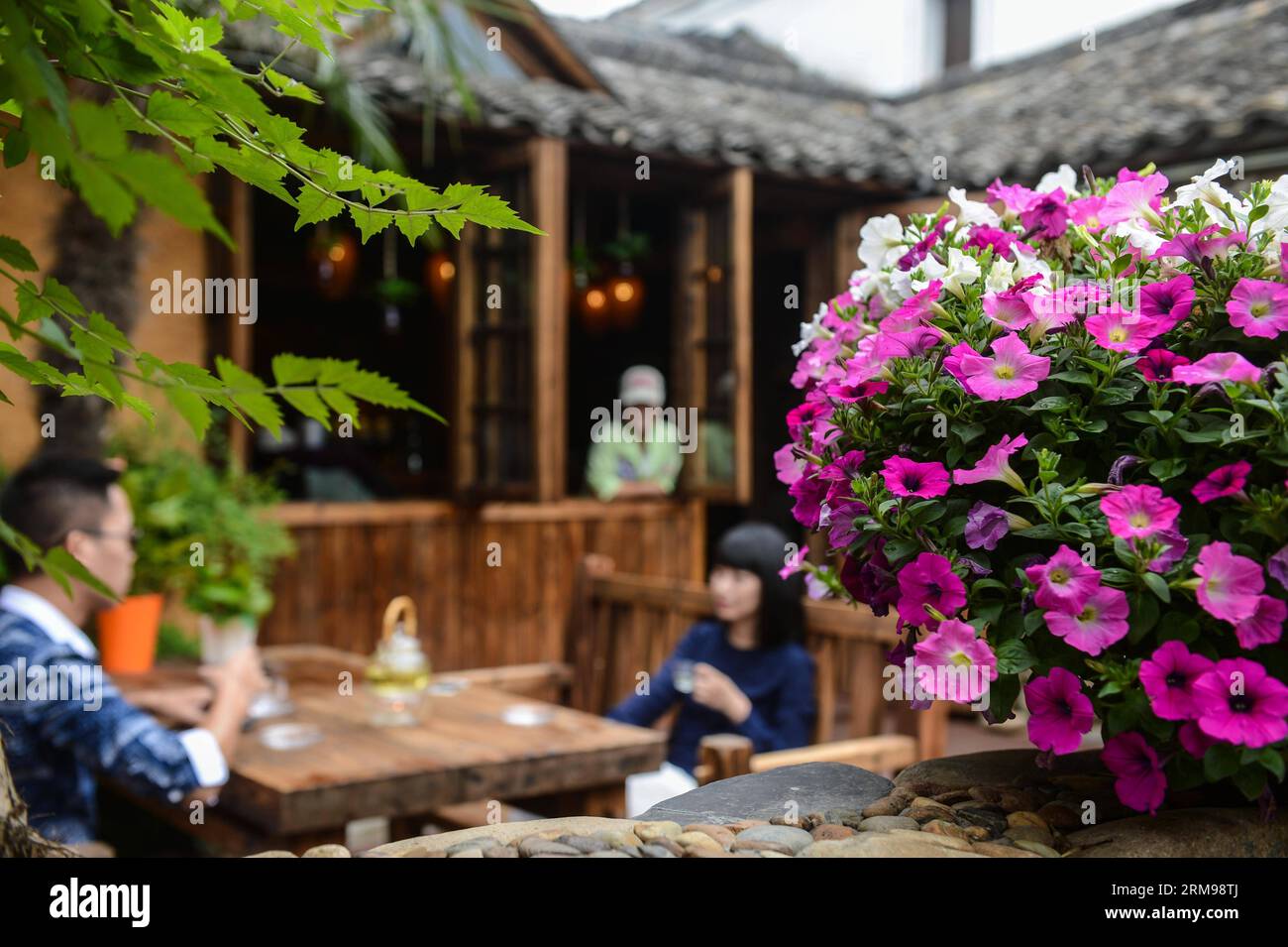 (140513) -- TONGLU, May 13, 2014 (Xinhua) -- Tourists have tea at the swinery tea bar in Dipu Village of Jiangnan Town in Tonglu County, east China s Zhejiang Province, May 13, 2014. Dipu Village, a national historical and cultural village with nearly a thousand years history, has committed to environment reform, village protection and tourism development for the past few years. The swinery tea bar sets a successful example of the transform. The bar used to be five messy stone houses for pigs keeping. After renovation, it functions as a modern tea bar with traditional appearance, attracting ma Stock Photo