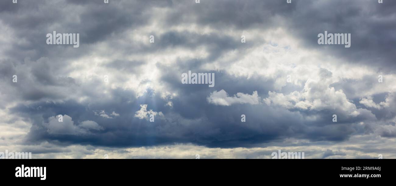 Cumuliform cloudscape before the rain. Dramatic dark sky background. The sun is hidden. Stock Photo