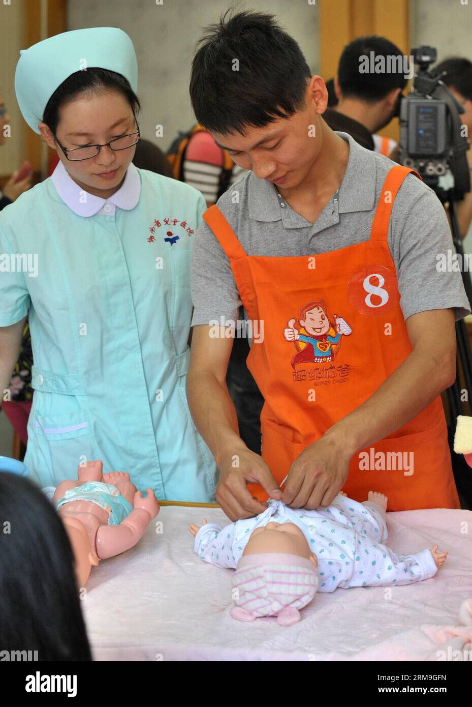 (140523) -- CHANGSHA, May 23, 2014 (Xinhua) -- A father learns dressing a baby at a Super Daddy Training Camp at Hunan Provincial Children Hospital in Changsha, capital of central China s Hunan Province, May 23, 2014. A total of 40 daddies took part in the camp and they would learn baby nurturing skills in a short time under the guidance of paediatricians. (Xinhua/Long Hongtao) (lfj) CHINA-HUNAN-CHANGSHA-SUPER DADAY TRAINING CAMP (CN) PUBLICATIONxNOTxINxCHN   Changsha May 23 2014 XINHUA a Father learns Dressing a Baby AT a Super Daddy Training Camp AT Hunan Provincial Children Hospital in Chan Stock Photo