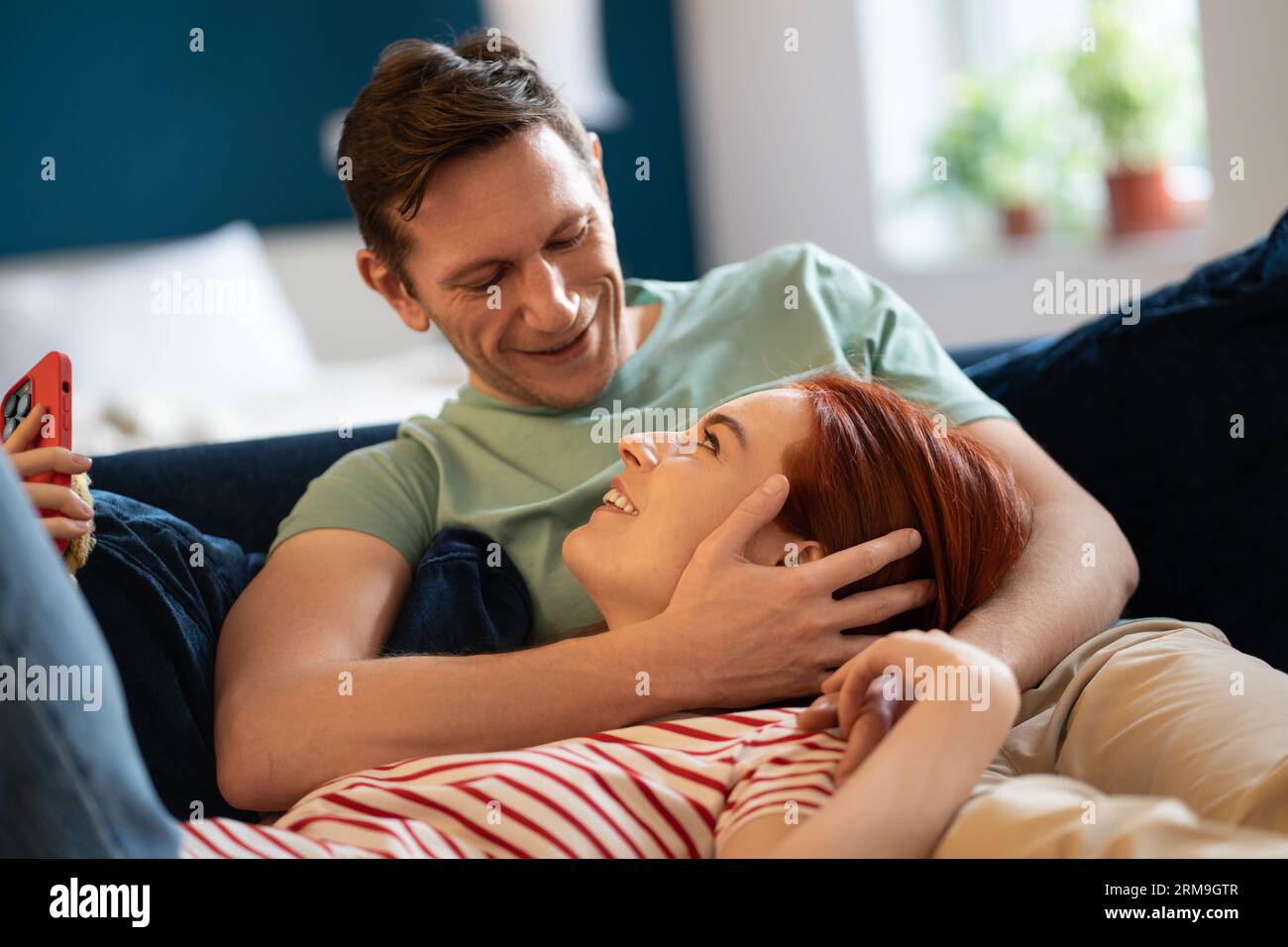 Happy family couple lovingly look at each other relaxing lying on sofa ...