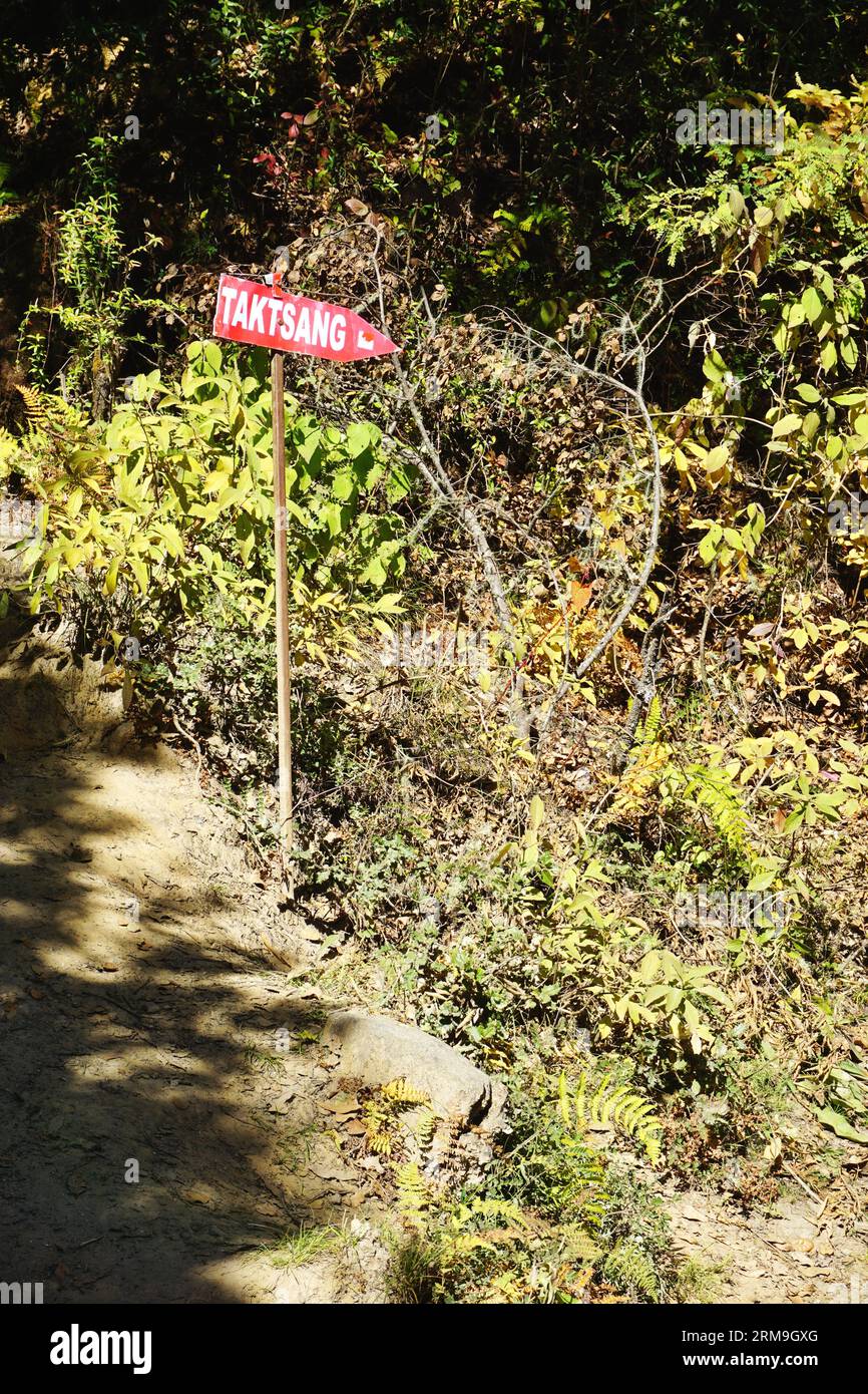 Red painted sign points the way on the trail to Taktsang, Bhutan's famous Tiger's Nest Monastery near Paro, Bhutan. The 2-mile trail climbs 1,699 feet Stock Photo