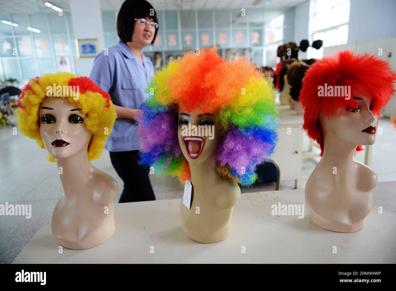 A worker examines wigs designed for soccer fans at Jifa Group in Jimo City,  east China s Shandong Province, May 24, 2014. As the World Cup Brazil  approaches, wig producer Jifa Group