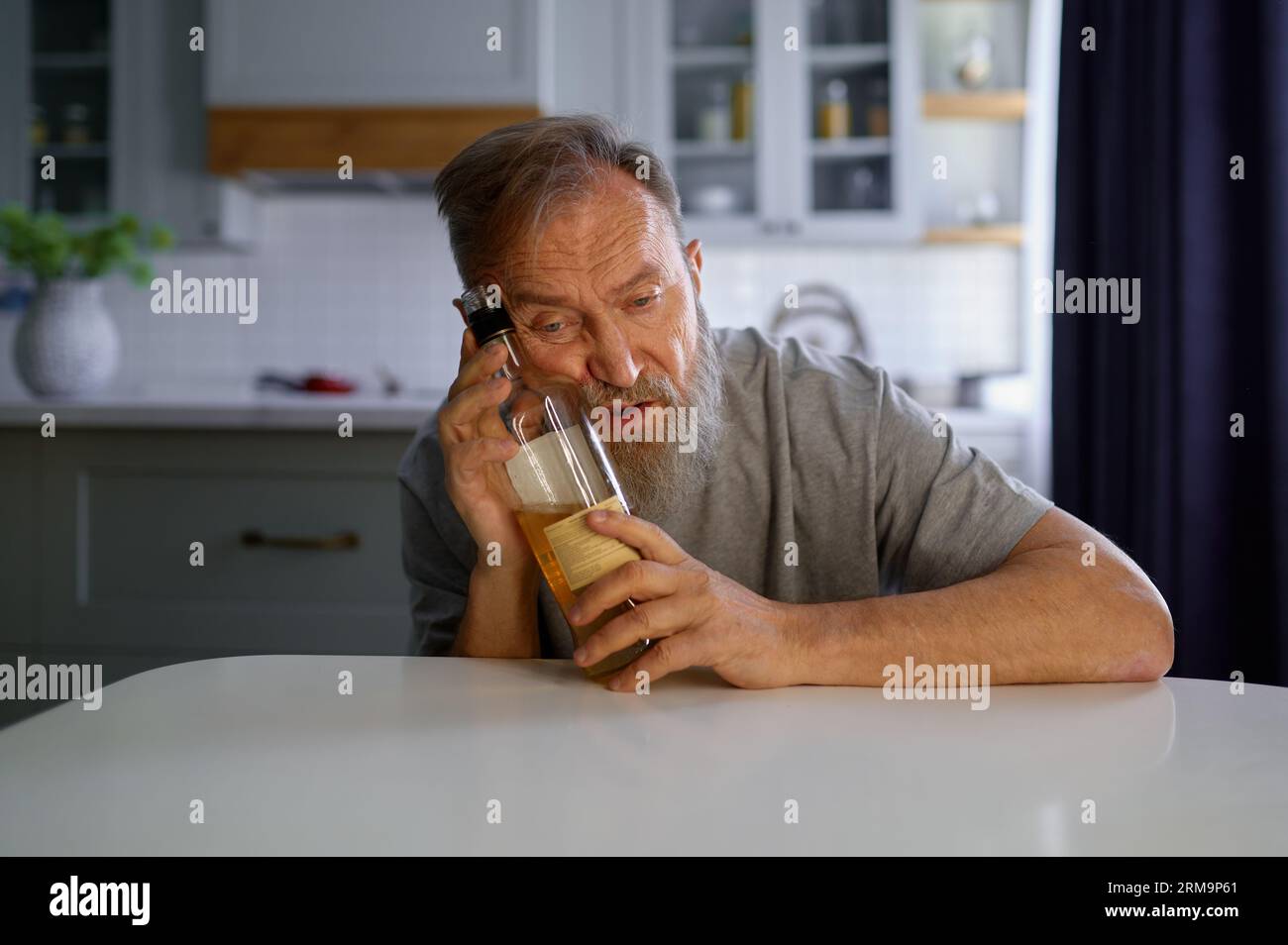 Portrait of lonely drunk man feeling depressed on home kitchen Stock Photo