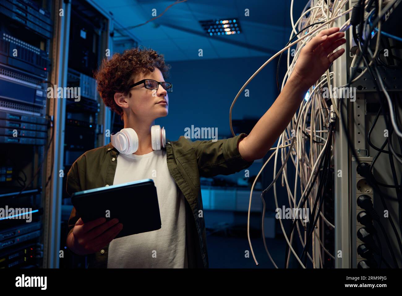 Side view of young teenager boy checking wires connection in server ...