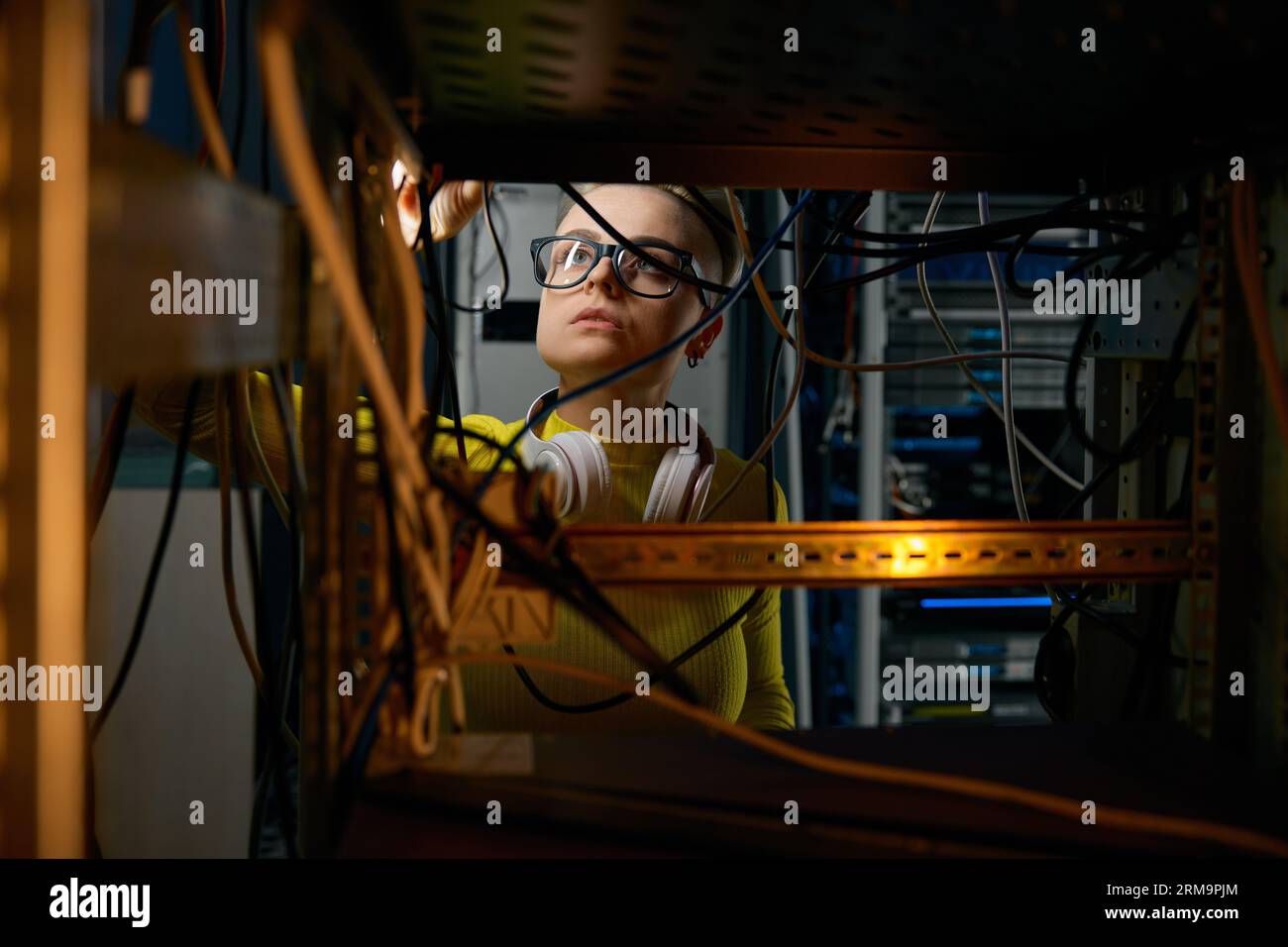 Young woman IT engineer working in datacenter room connecting cables Stock Photo