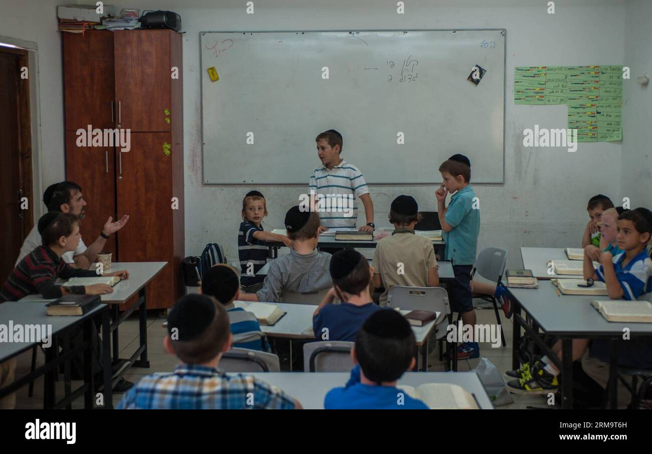 Tzviel Noyman (C) talks with his teacher (1st L Rear) when leading a class of Jewish religion at Torat Moshe elementary school in Beit Shemesh, about 20 km from Jerusalem, on May 29, 2014. Tzviel Noyman is an Israeli Ultra-Orthodox boy in a family with six children, three boys and three girls. He is ten years old this year and a grade three pupil of Torat Moshe elementary school, which is only opened to Jewish children. Tzviel has eight classes each day, including Hebrew, English, mathematics and Jewish religion, which has four classes each day including Talmud, Mishnah and Gemara. Tzviel like Stock Photo